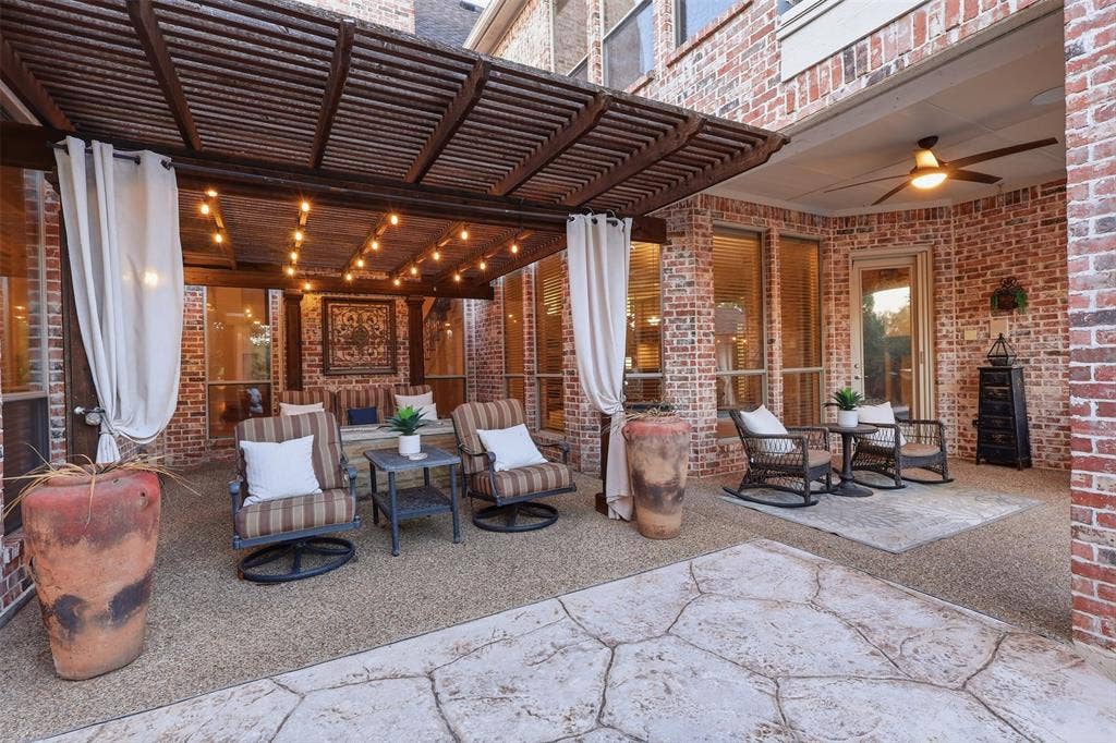 1919 Kings Pass, Heath, TX 75032 Covered patio featuring a wood-slat pergola, string lighting, exposed brick walls, a ceiling fan, and textured concrete flooring