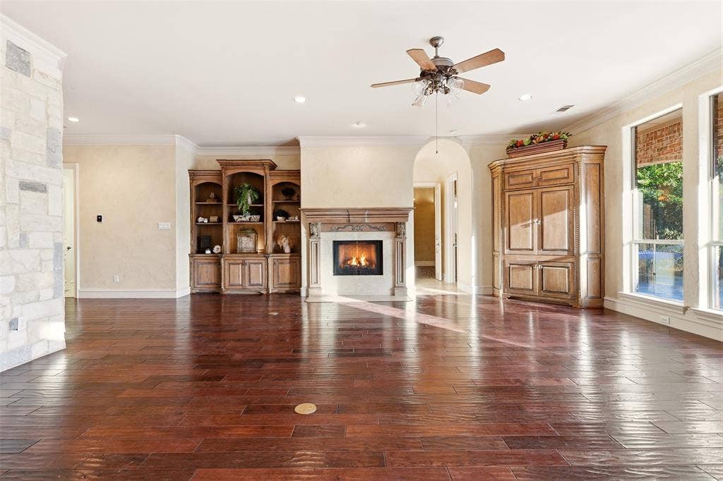 1919 Kings Pass, Heath, TX 75032 Hardwood flooring, stone accent wall, decorative fireplace with mantel, built-in cabinetry, and ceiling fan with lighting