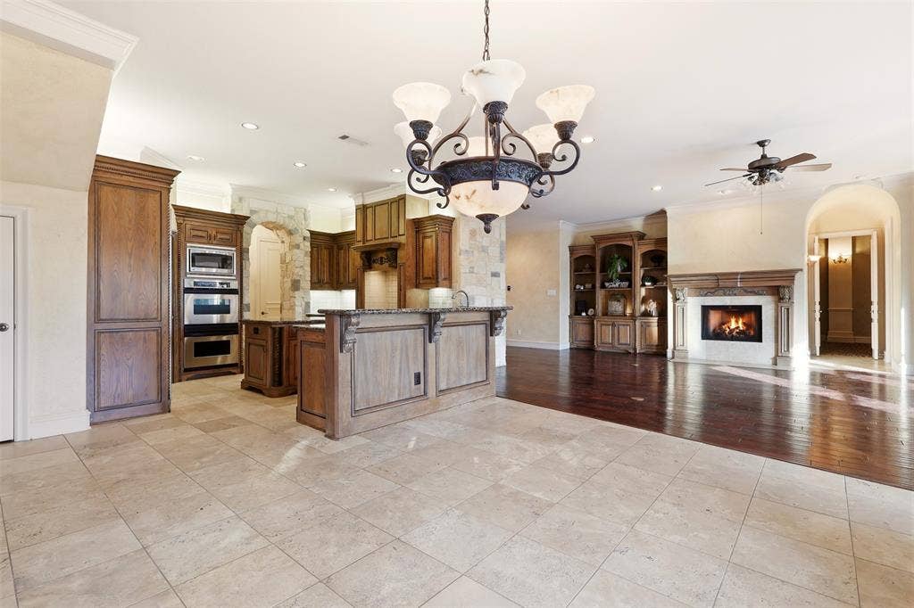 1919 Kings Pass, Heath, TX 75032 Stone tile flooring, wood-finish cabinetry, stainless steel double oven, built-in shelving, and a stone fireplace with a wood-finish mantel