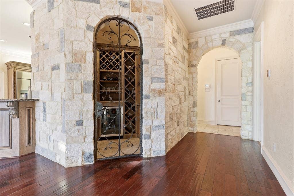 1919 Kings Pass, Heath, TX 75032 Stone accent wall with an arched entryway and a built-in wine cellar featuring a wrought iron gate