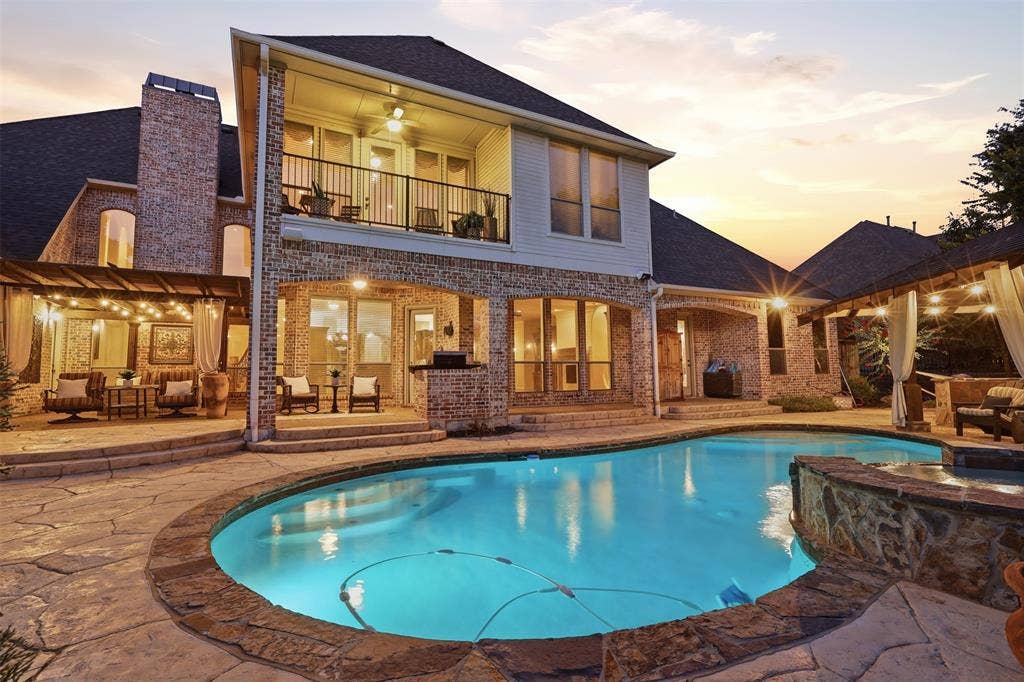 1919 Kings Pass, Heath, TX 75032 Rear exterior featuring a stone patio, built-in swimming pool, covered outdoor living area, and a second-story balcony