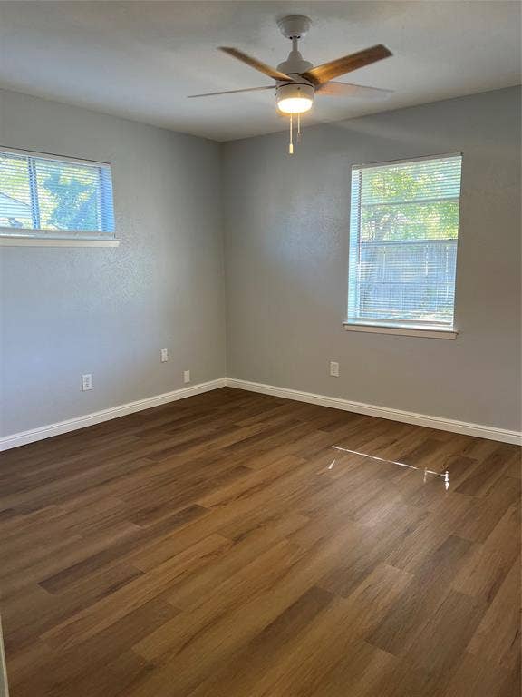 102 Silver Creek Drive, Duncanville, TX 75137 Room featuring wood-finish flooring, neutral walls, two windows, and a ceiling fan with integrated light fixture