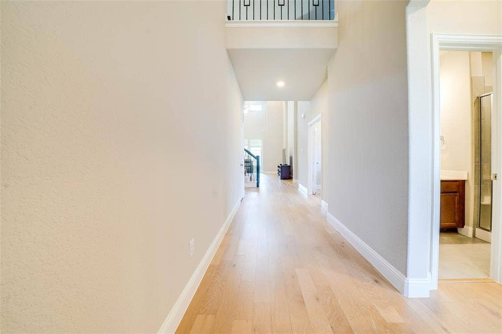 Hallway featuring light wood-style flooring and a high ceiling