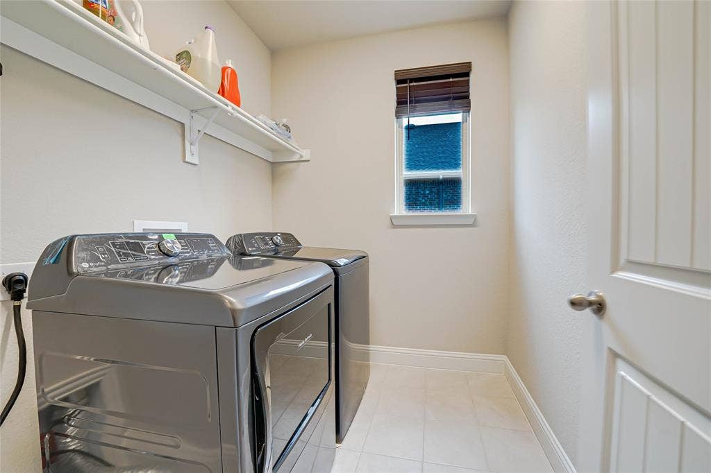 Laundry area featuring washing machine and dryer and light tile patterned flooring