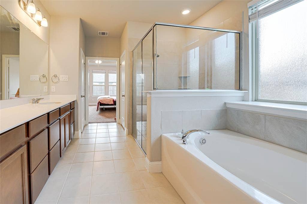 Ensuite bathroom with light tile patterned floors, vanity, a stall shower, and a bath