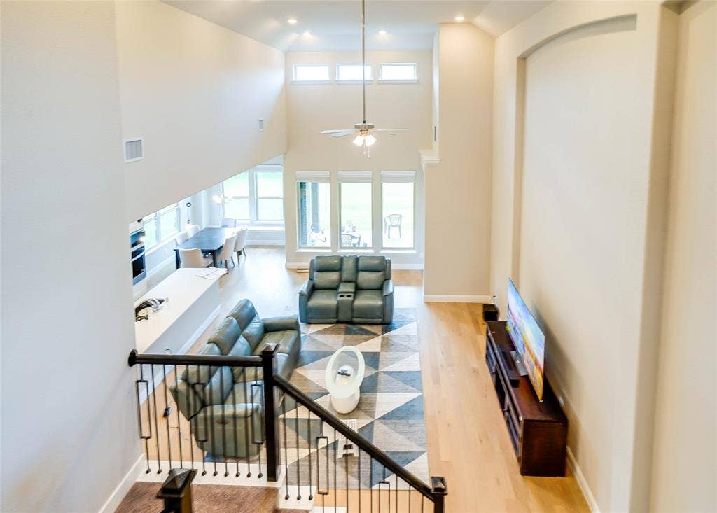 Stairway featuring wood finished floors, ceiling fan, a high ceiling, and recessed lighting