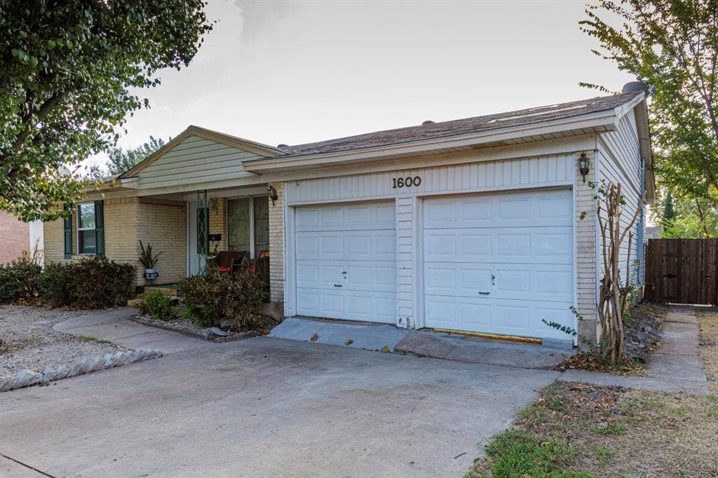 1600 Summit Street, Mesquite, TX 75149 Single-story exterior featuring light-toned brick masonry, white vertical siding, an attached two-car garage, and a concrete driveway