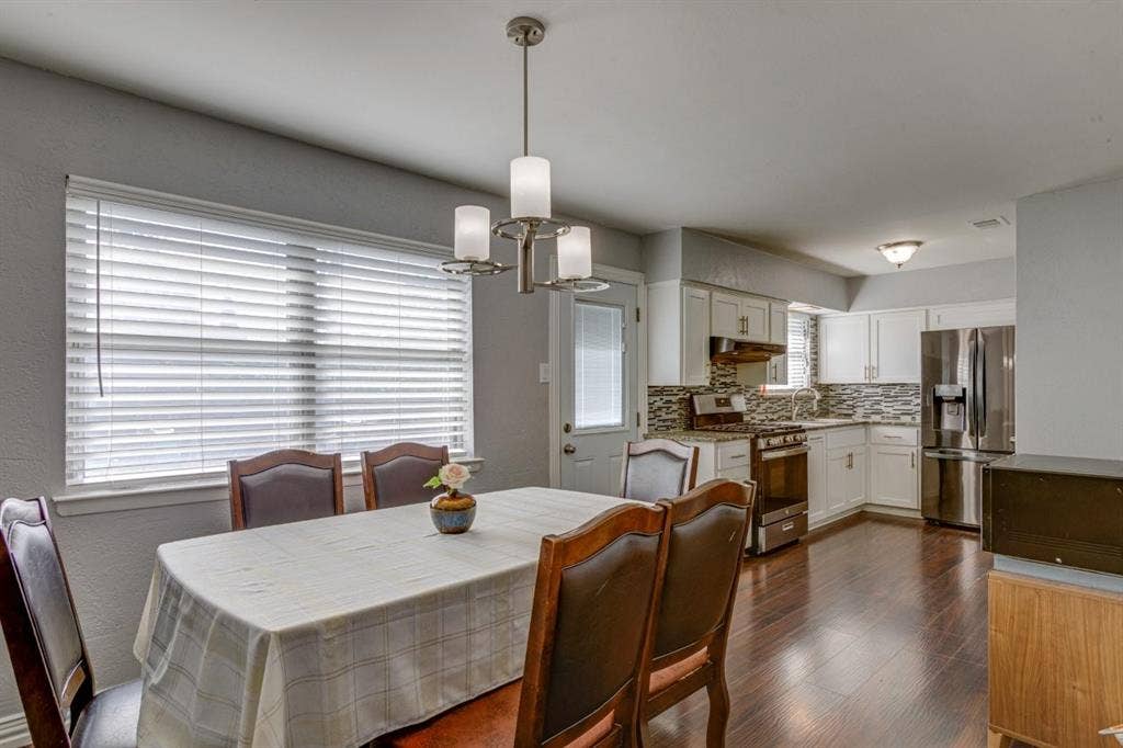 1600 Summit Street, Mesquite, TX 75149 Kitchen featuring white cabinetry, wood-finish flooring, stainless steel appliances, multi-toned tile backsplash, and a three-light chandelier