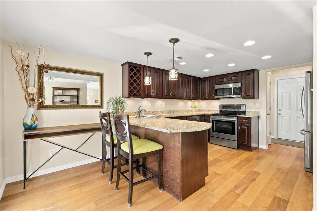2524 Brooke Trail, Carrollton, TX 75006 Kitchen featuring dark Kraftmaid cabinets, granite counter tops, and stainless steel appliances.