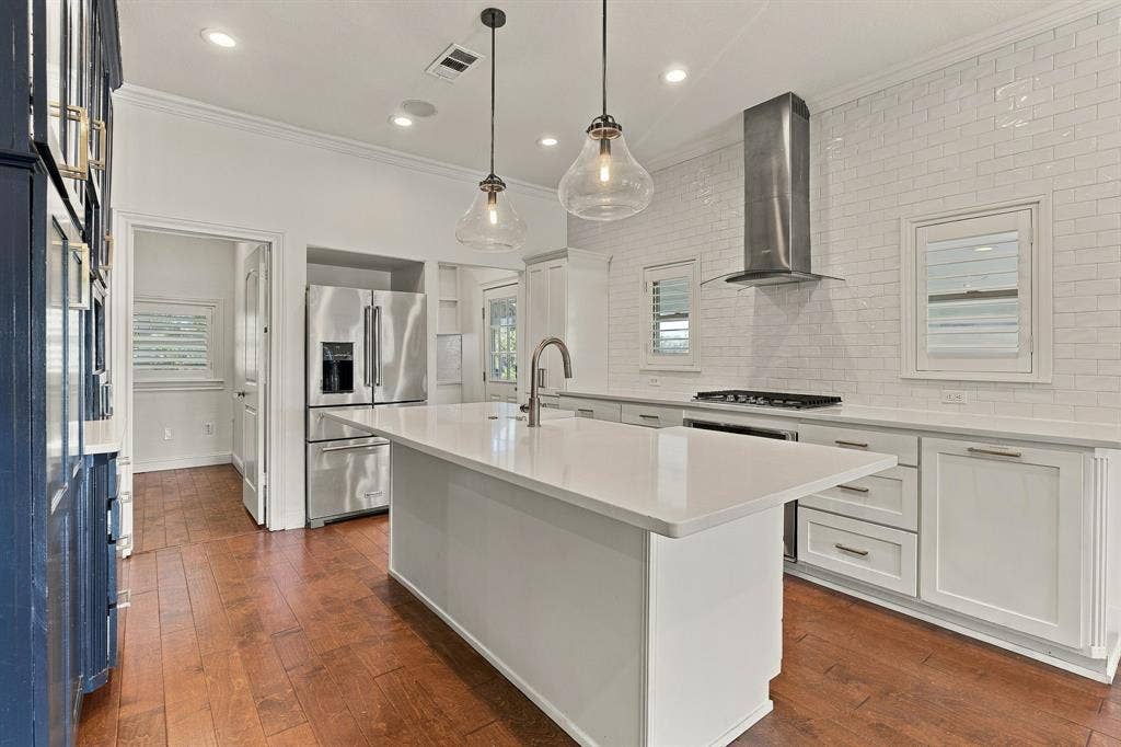 510 E Malone Street, Celina, TX 75009 Kitchen featuring wood-finish flooring, a central island with a stone-finish countertop, stainless steel appliances, a white subway tile backsplash, and glass pendant lighting