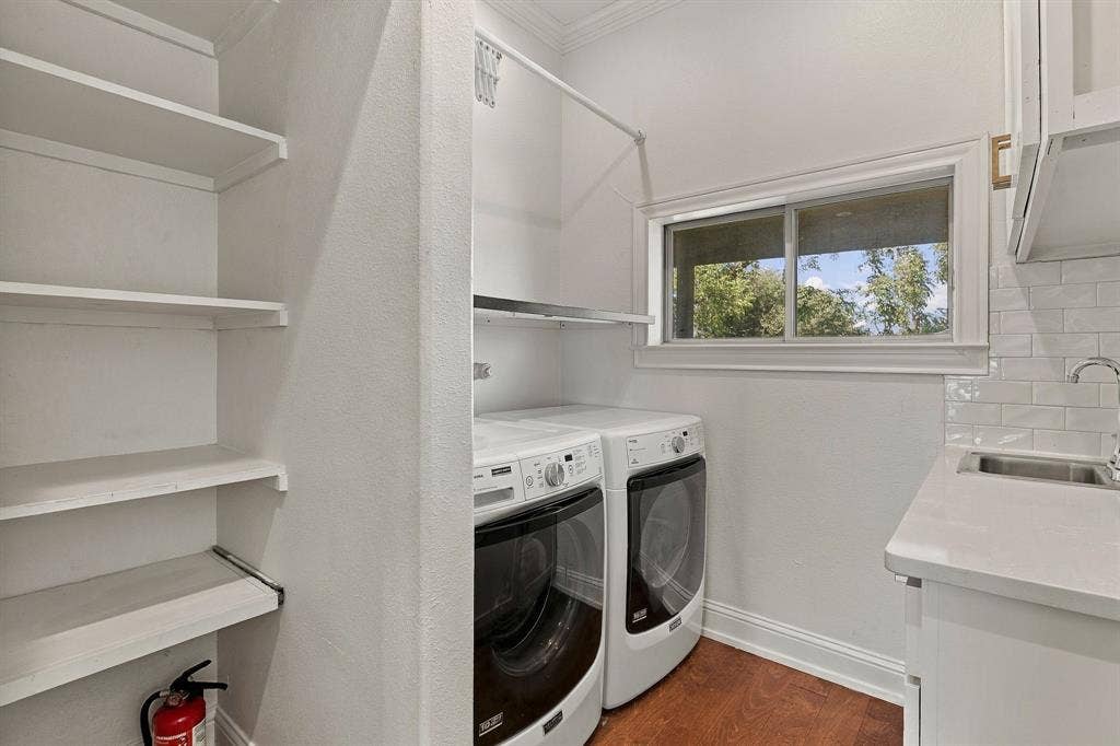510 E Malone Street, Celina, TX 75009 Laundry room featuring custom built-in shelving, a light-toned solid surface countertop, an undermount sink, subway tile backsplash, and wood-finish flooring