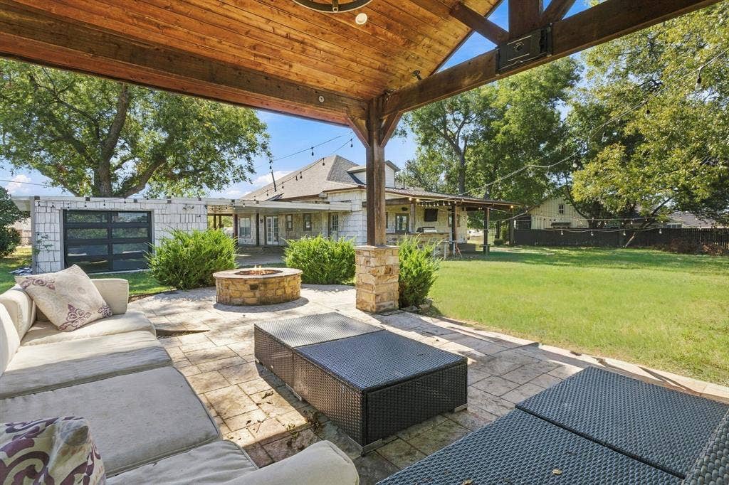 510 E Malone Street, Celina, TX 75009 Covered patio featuring a timber-frame ceiling, stone-clad support columns, stone-finished fire pit, and stone-paver hardscaping