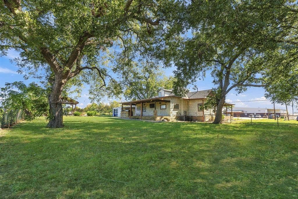 510 E Malone Street, Celina, TX 75009 Stone exterior home featuring a covered front porch, expansive lawn, and mature trees