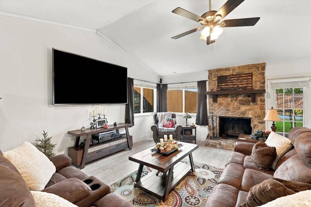 2117 Northmoor Drive, Carrollton, TX 75006 Vaulted ceiling, floor-to-ceiling stone fireplace, heavy timber mantel, wood-finish flooring, and ceiling fan