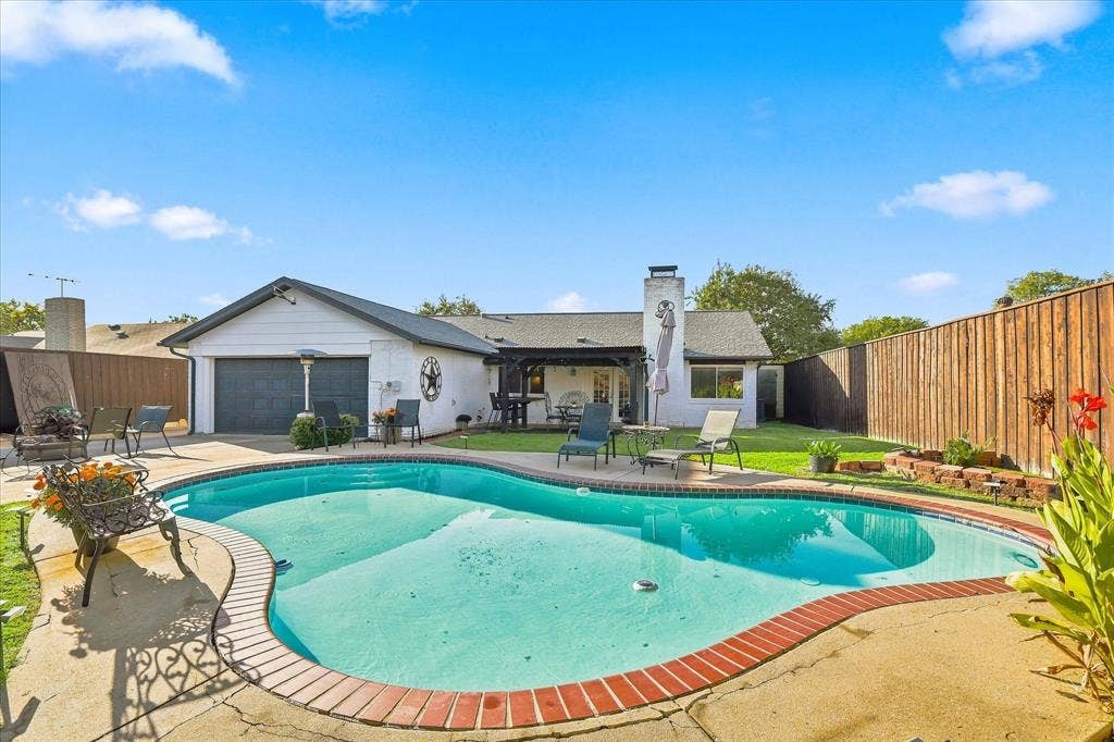 2117 Northmoor Drive, Carrollton, TX 75006 Backyard featuring an in-ground swimming pool with brick coping, a concrete deck, a covered patio, and wood privacy fencing