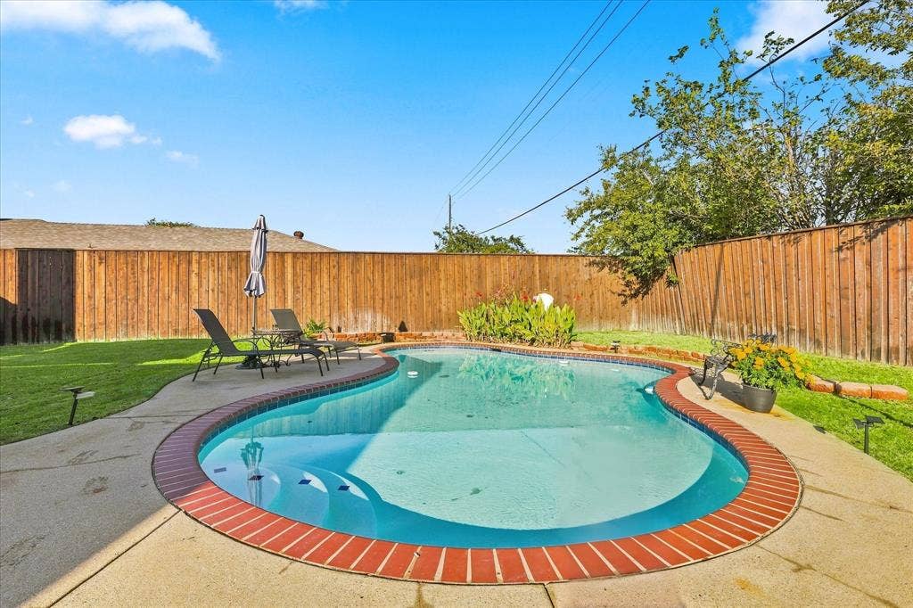 2117 Northmoor Drive, Carrollton, TX 75006 Free-form swimming pool with brick coping, concrete decking, and perimeter wood fencing