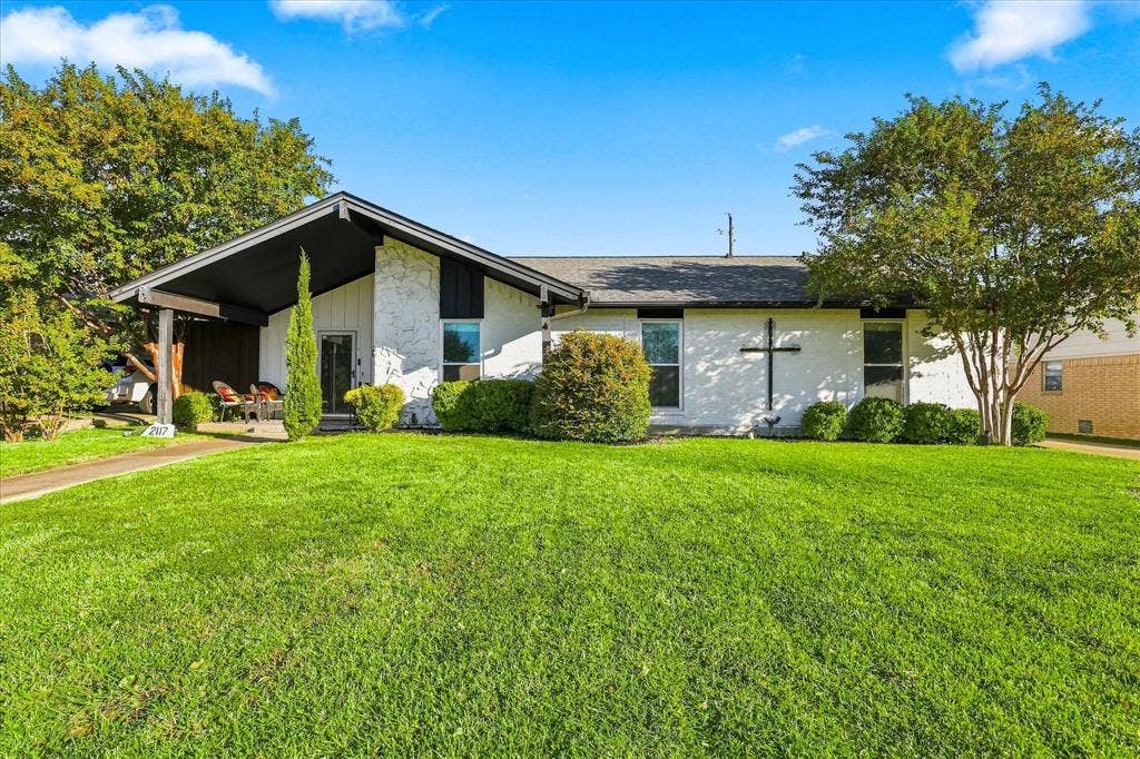 2117 Northmoor Drive, Carrollton, TX 75006 Mid-century modern architectural style featuring a painted brick exterior, a covered front porch, and an expansive front lawn with mature landscaping