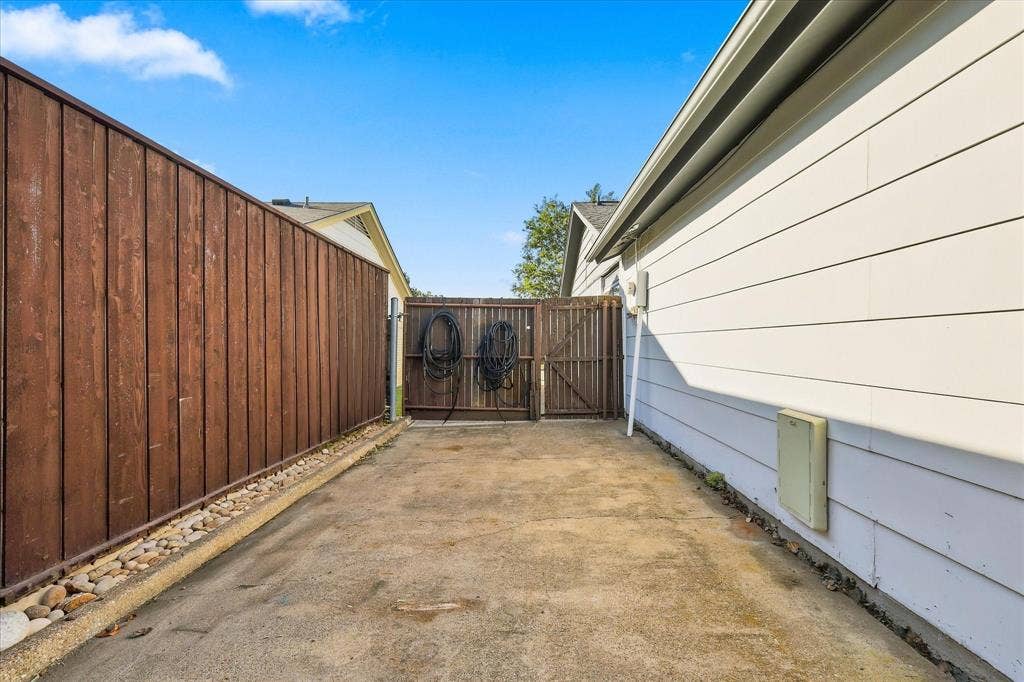 2117 Northmoor Drive, Carrollton, TX 75006 Concrete side yard featuring horizontal siding, a stained wood privacy fence, and a stone-lined border