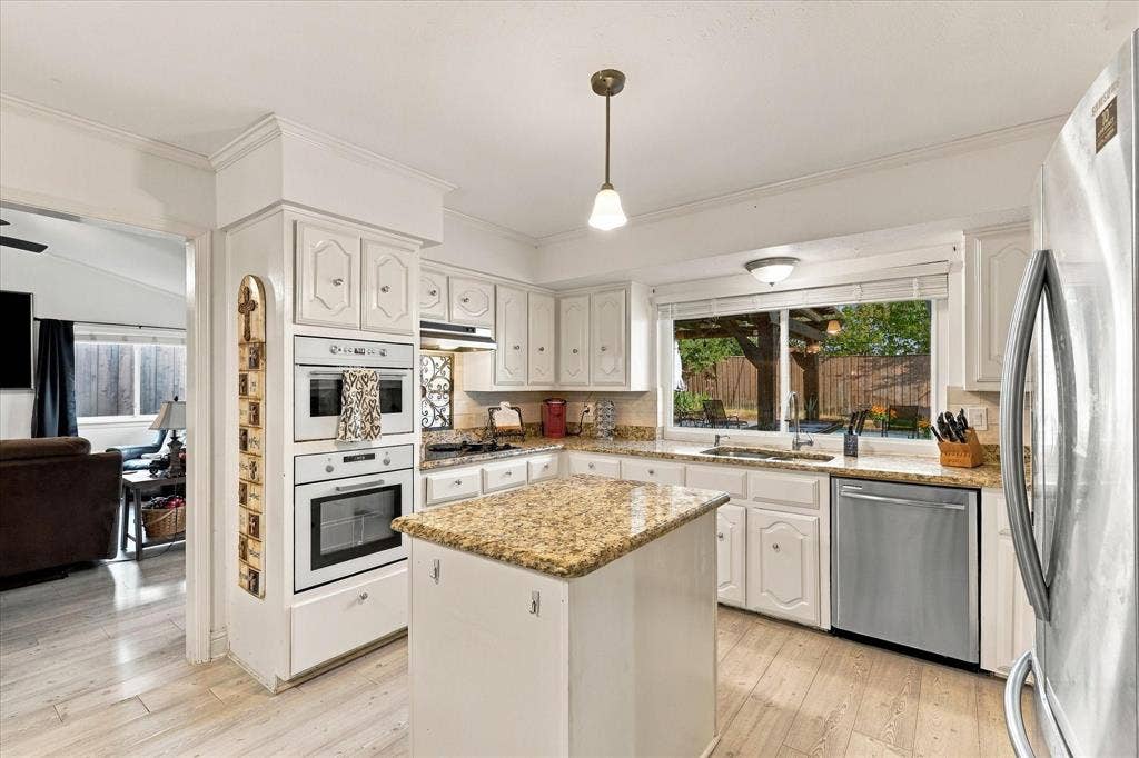 2117 Northmoor Drive, Carrollton, TX 75006 Kitchen featuring white cabinetry, stone-surface countertops, center island, integrated wall ovens, and stainless steel dishwasher