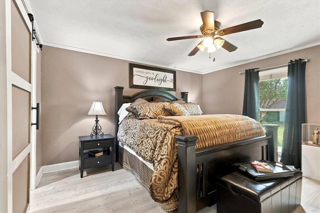 2117 Northmoor Drive, Carrollton, TX 75006 Neutral-toned walls featuring wood-finish flooring, a ceiling fan with integrated lighting, and a sliding barn-style door