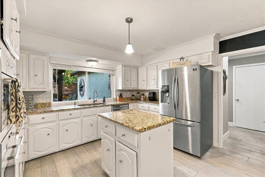 2117 Northmoor Drive, Carrollton, TX 75006 Kitchen featuring white cabinetry, stone-surface countertops, central island, stainless steel refrigerator, and wood-finish flooring