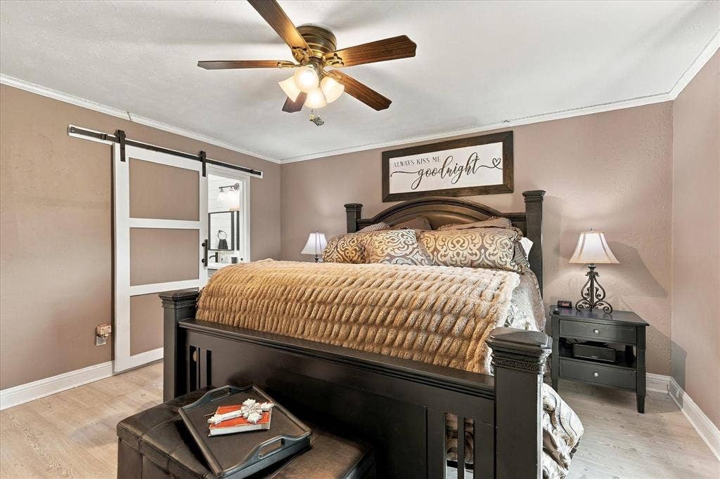 2117 Northmoor Drive, Carrollton, TX 75006 Wood-finish flooring, sliding barn door with black hardware, and a ceiling fan with integrated lighting