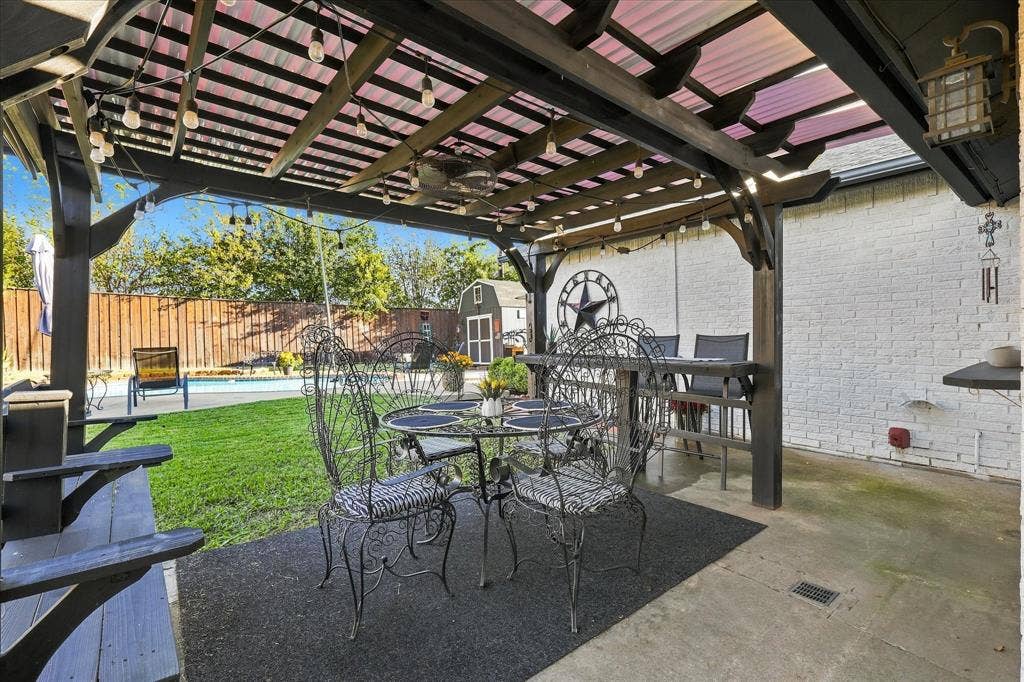 2117 Northmoor Drive, Carrollton, TX 75006 Covered outdoor pergola featuring a wooden timber frame, integrated ceiling fan, and painted brick exterior wall