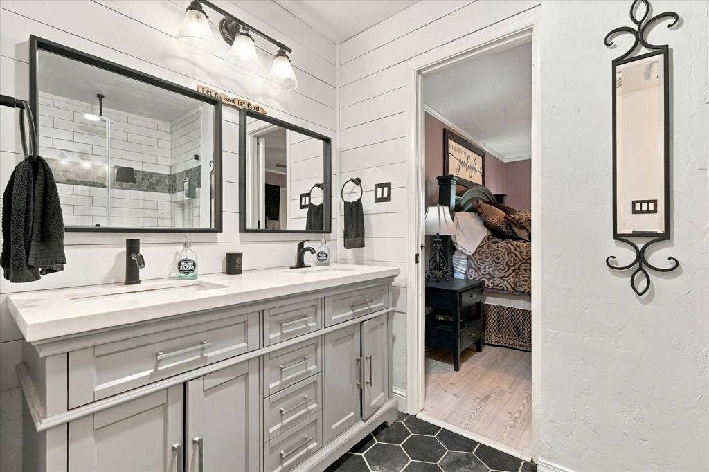 2117 Northmoor Drive, Carrollton, TX 75006 Double vanity featuring a white composite countertop, undermount sinks, matte black fixtures, shiplap wall accents, and hexagonal floor tiling