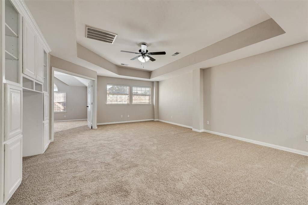 2017 Lunenburg Drive, Allen, TX 75013 Room featuring a tray ceiling, built-in white cabinetry, wall-to-wall carpeting, and a ceiling fan with integrated lighting