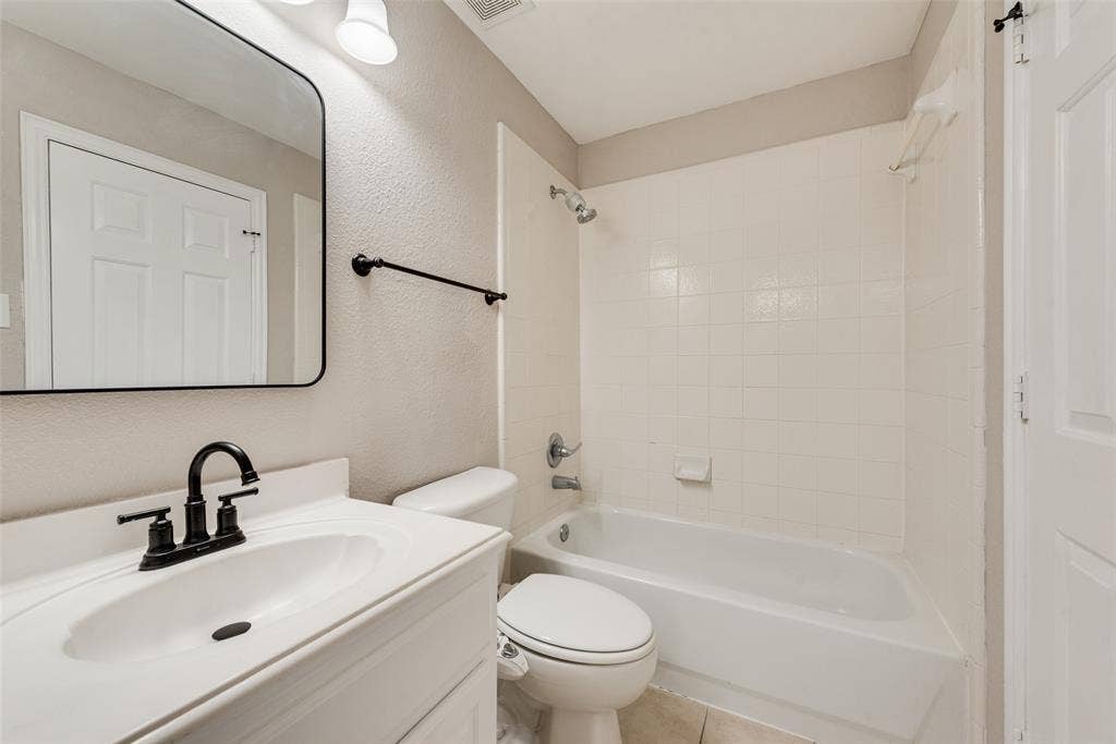 2017 Lunenburg Drive, Allen, TX 75013 Bathroom featuring a vanity with a white countertop and oval sink, matte black widespread faucet, rectangular mirror with black frame, and a shower-tub combination with white tile surround