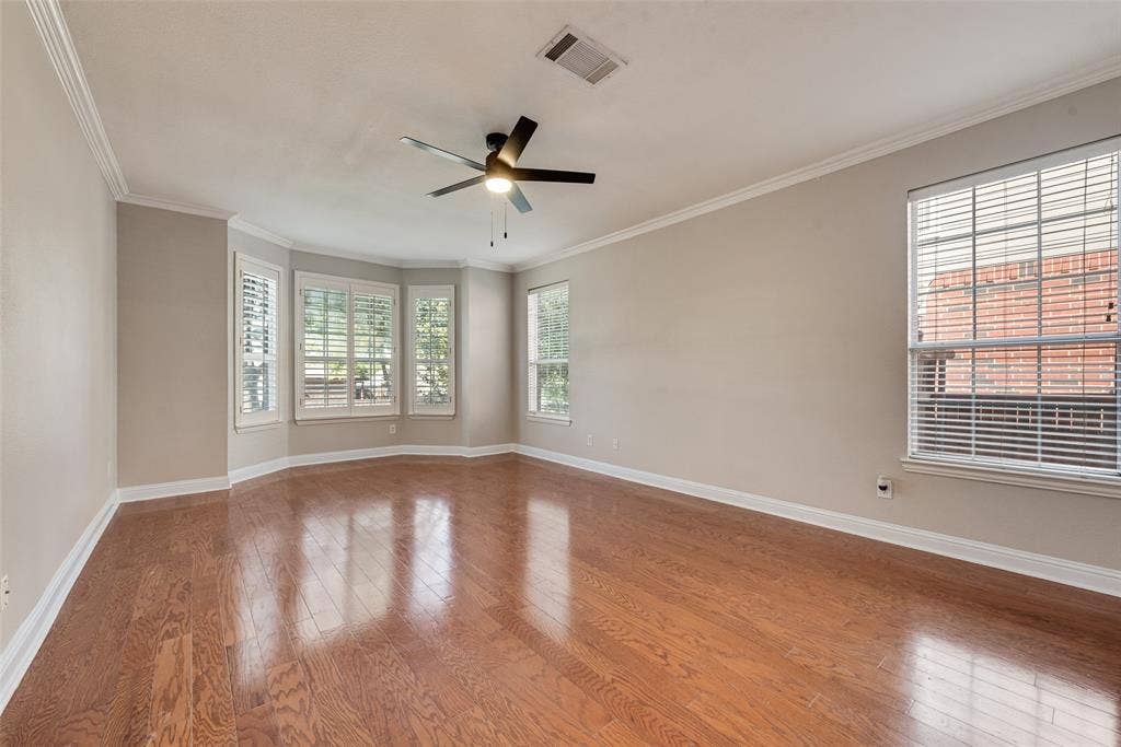 2017 Lunenburg Drive, Allen, TX 75013 Spacious room featuring wood-finish flooring, crown molding, multiple windows with plantation shutters, and a ceiling fan