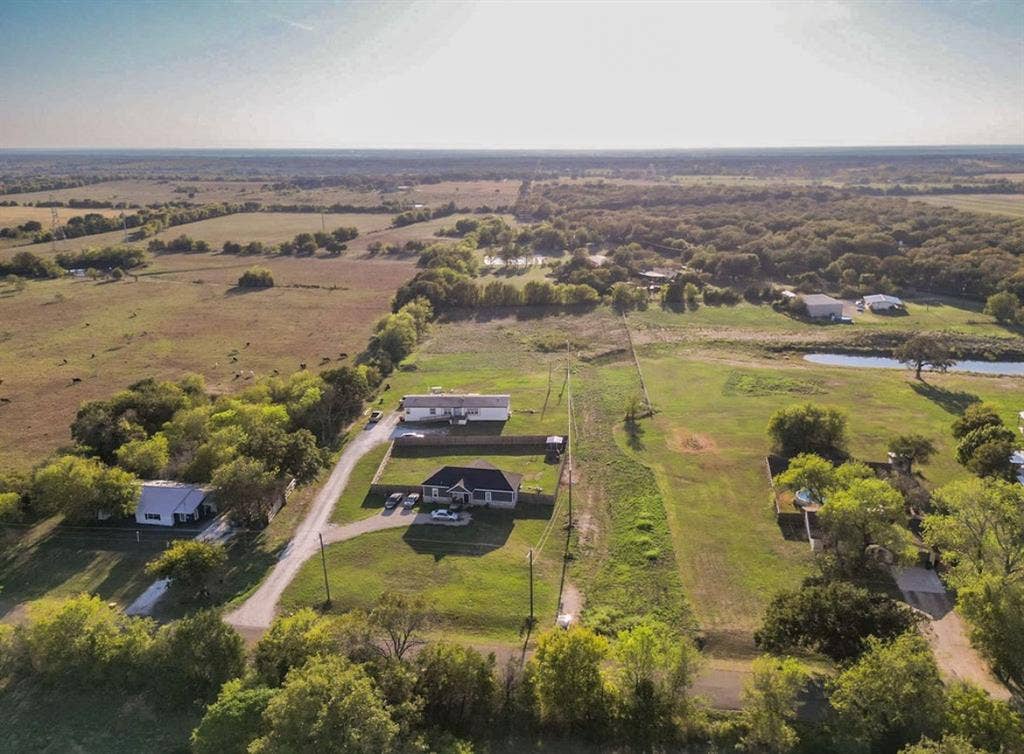3659 N Katy Road, Ross, TX 76640 Aerial view of expansive acreage featuring multiple structures, fenced perimeter sections, gravel driveways, and mature tree clusters
