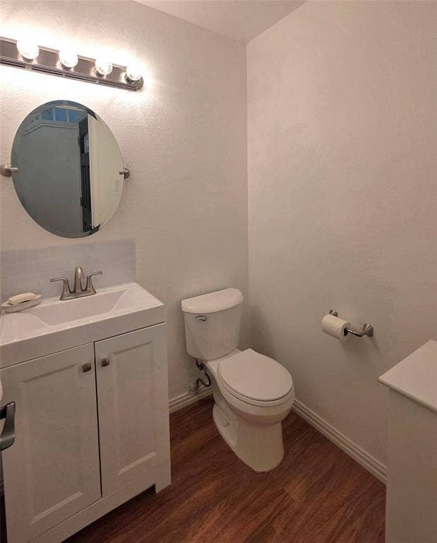 9436 Penny Lane, Irving, TX 75063 White vanity with a rectangular basin, oval wall-mounted mirror, four-light vanity fixture, wood-finish flooring, and subway tile backsplash
