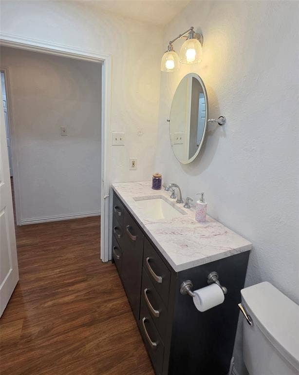9436 Penny Lane, Irving, TX 75063 Dark-toned vanity with multi-drawer storage, integrated sink, light-colored patterned countertop, oval wall-mounted mirror, and dual-globe light fixture