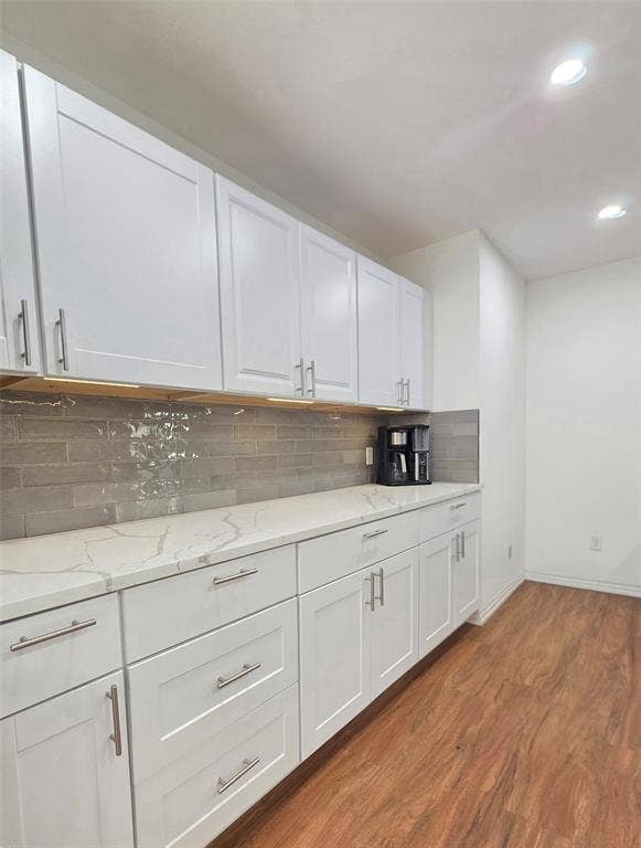 9436 Penny Lane, Irving, TX 75063 White shaker-style cabinetry, quartz countertops, gray subway tile backsplash, under-cabinet lighting, and wood-finish flooring