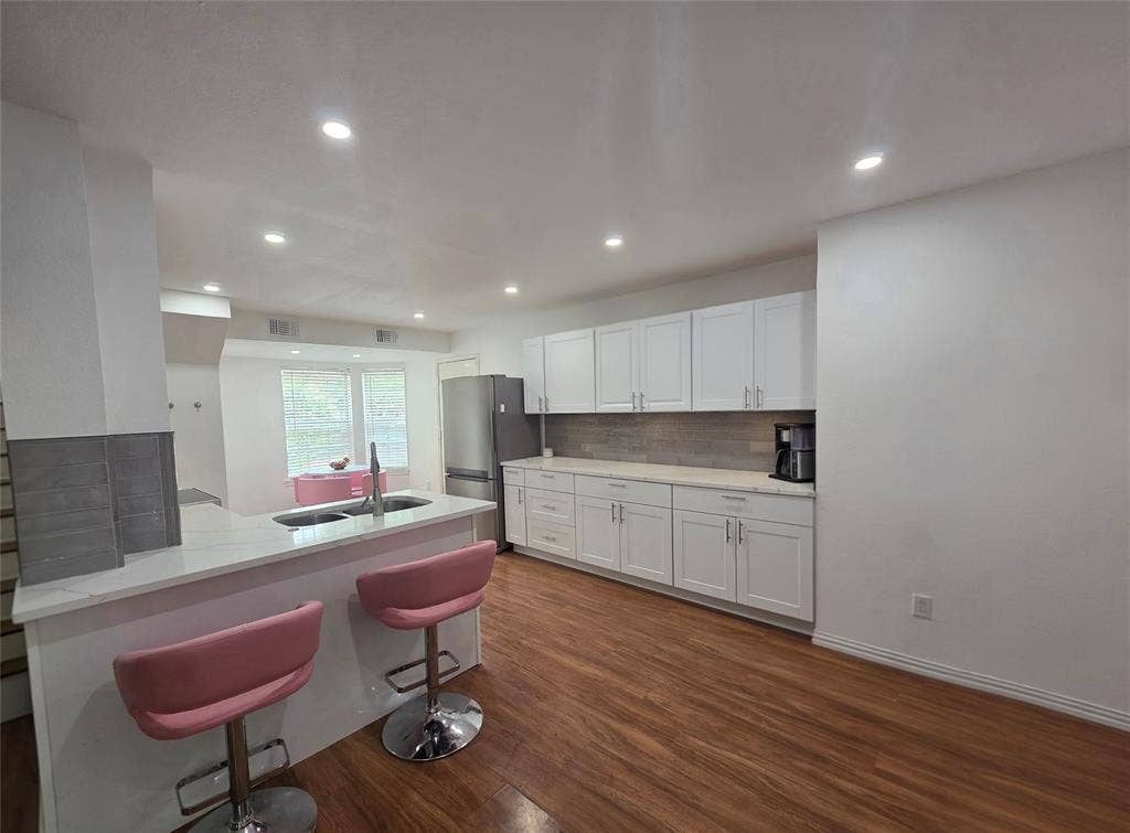 9436 Penny Lane, Irving, TX 75063 Kitchen Dining bar featuring white shaker-style cabinetry, quartz countertops, a peninsula with a stainless steel undermount sink, wood-finish flooring, and recessed ceiling lighting