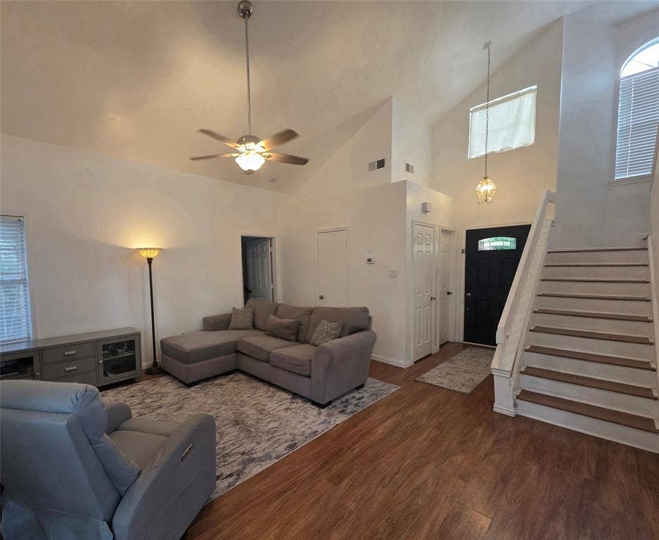 9436 Penny Lane, Irving, TX 75063 Vaulted ceiling featuring a central hanging ceiling fan, wood-finish flooring, staircase with wood-tread steps, and a decorative transom window above the front entrance