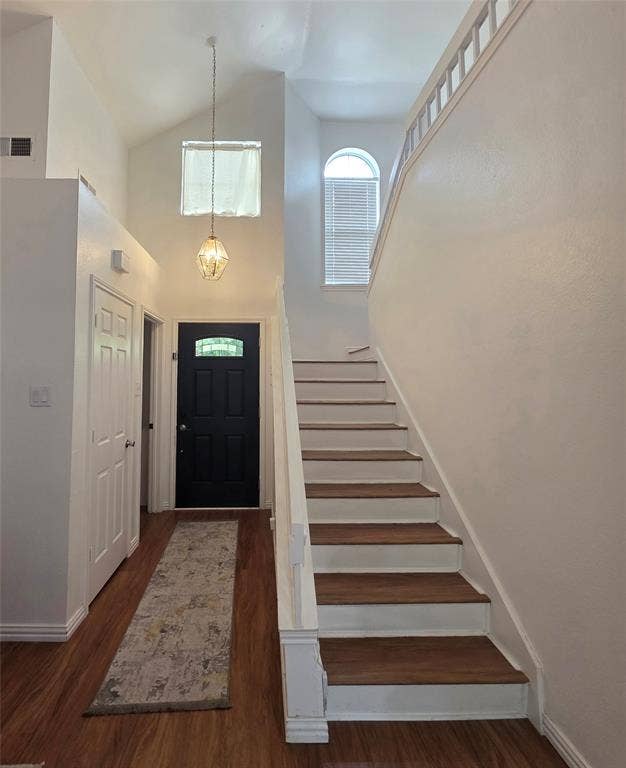 9436 Penny Lane, Irving, TX 75063 Entryway featuring high ceilings, wood-finish flooring, a pendant light fixture, a staircase with wood-finish treads and white risers, and an arched window