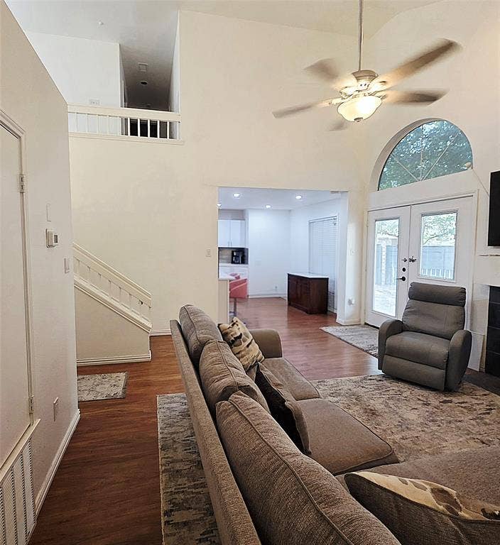 9436 Penny Lane, Irving, TX 75063 Vaulted ceilings, wood-finish flooring, an arched window, a built-in staircase with a railing, and a ceiling-mounted light fixture