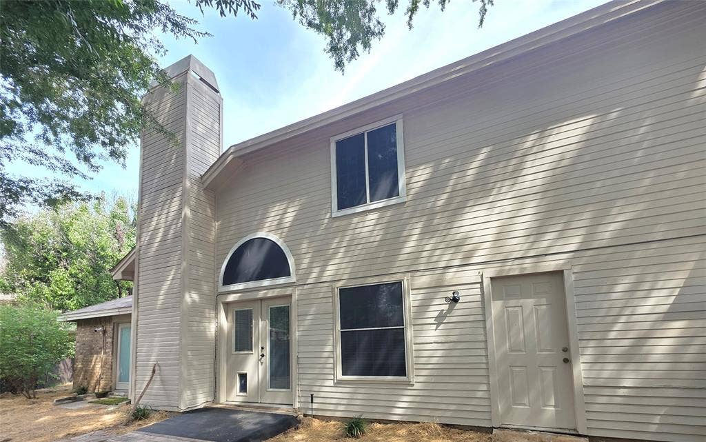 9436 Penny Lane, Irving, TX 75063 Exterior facade featuring horizontal siding, a prominent chimney, an arched window, and double entry doors
