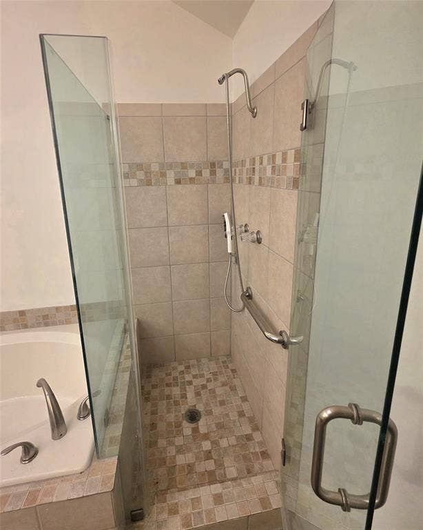 9436 Penny Lane, Irving, TX 75063 Walk-in shower featuring a glass enclosure, wall-mounted showerhead, tiled surround with a decorative mosaic accent, and a built-in metal grab bar, accompanied by a soaking tub with deck-mounted fixtures