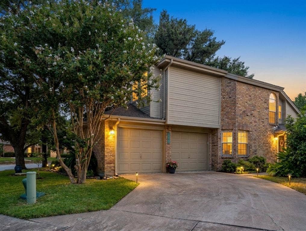 9436 Penny Lane, Irving, TX 75063 Exterior facade featuring brick and horizontal siding, two-car garage, and arched window detailing
