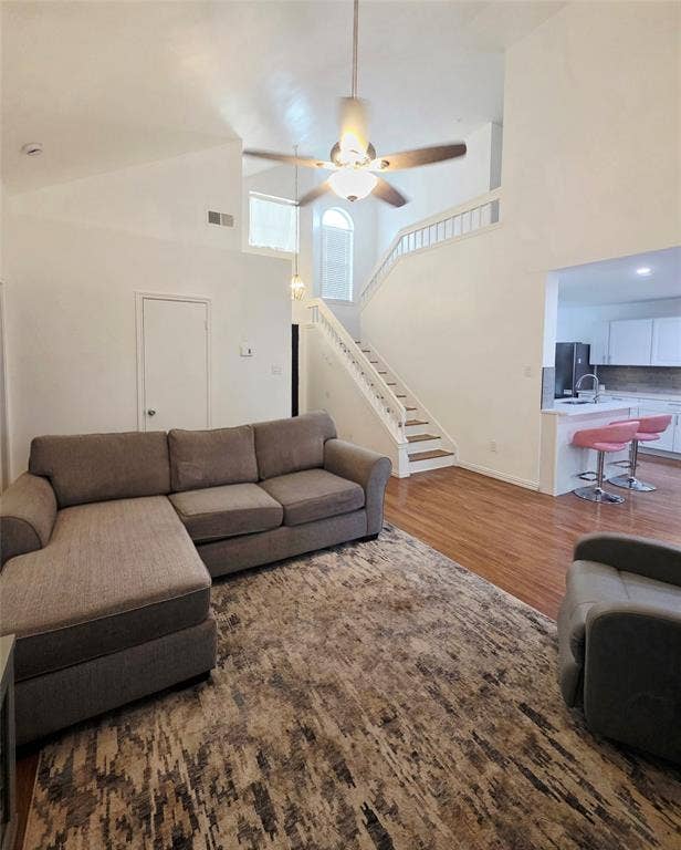 9436 Penny Lane, Irving, TX 75063 Vaulted ceilings, staircase with white railing, wood-finish flooring, arched window, and overhead ceiling fan
