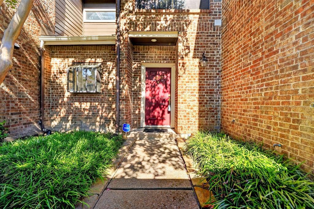 5859 Frankford Road, #1209, Dallas, TX 75252 Exterior entrance featuring a full-brick facade, a concrete walkway, a solid-color front door, and established ground-cover landscaping