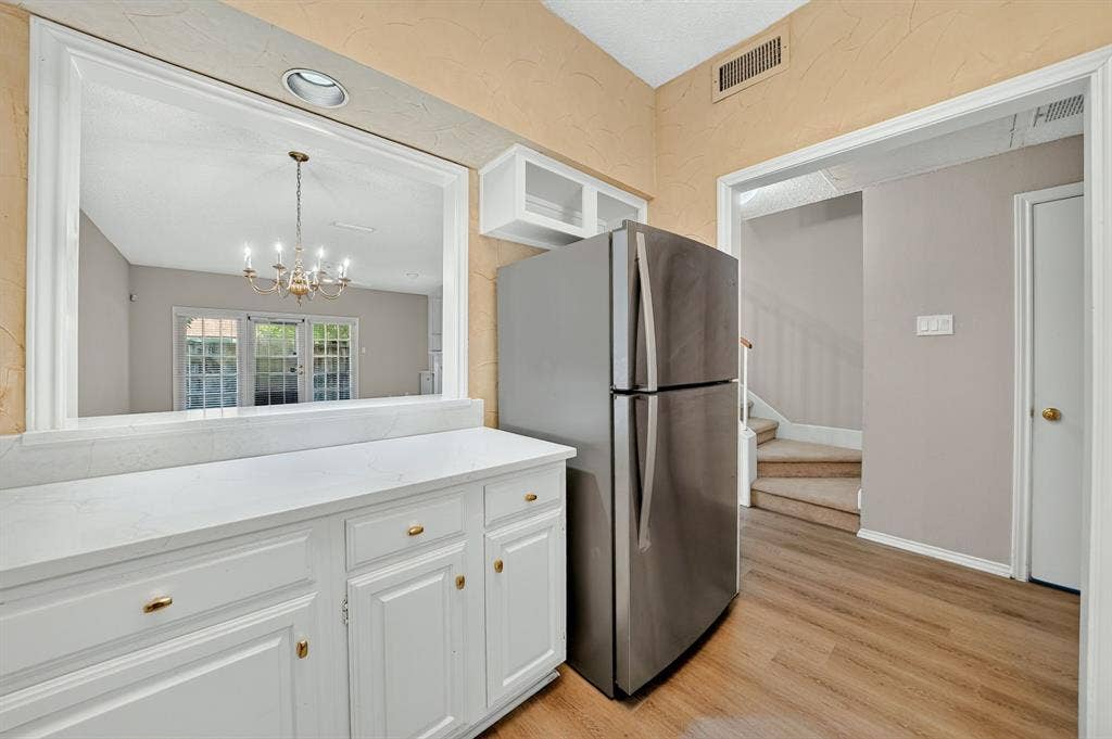 5859 Frankford Road, #1209, Dallas, TX 75252 White cabinetry with stone-finish countertops, stainless steel refrigerator, and wood-finish flooring