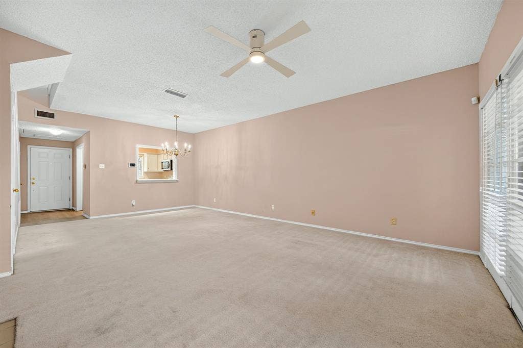5859 Frankford Road, #1209, Dallas, TX 75252 Expansive room featuring vaulted ceilings, a ceiling fan with integrated lighting, a pass-through opening, and sliding glass doors with window blinds