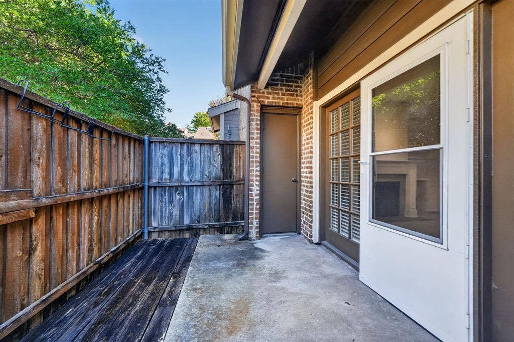 5859 Frankford Road, #1209, Dallas, TX 75252 Private outdoor patio featuring a concrete slab, wood-plank flooring, brick exterior masonry, and a wood privacy fence