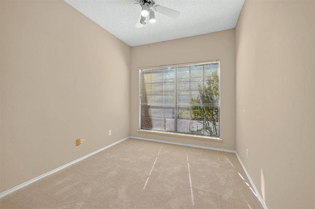 5859 Frankford Road, #1209, Dallas, TX 75252 Neutral-toned interior space featuring neutral carpeting, a large grid-pattern window, and a ceiling-mounted light fixture with a fan