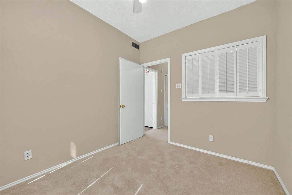 5859 Frankford Road, #1209, Dallas, TX 75252 Neutral-toned interior space featuring wall-to-wall carpeting, white plantation shutters, and a ceiling-mounted light fixture
