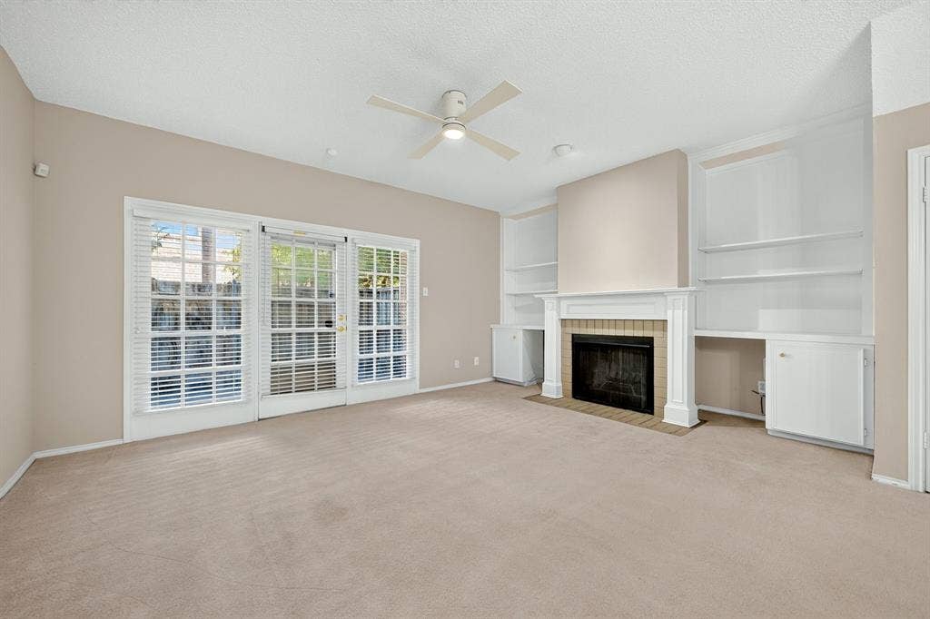 5859 Frankford Road, #1209, Dallas, TX 75252 Fireplace with tile surround, built-in cabinetry with integrated shelving, triple-panel glass doors, and a ceiling-mounted fan